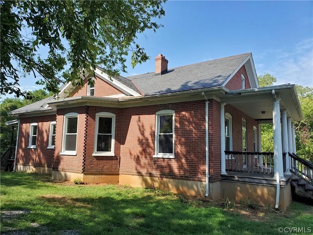 view of side of property featuring covered porch and a lawn