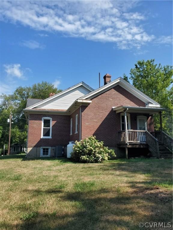 view of side of property with a yard, central AC, and a porch