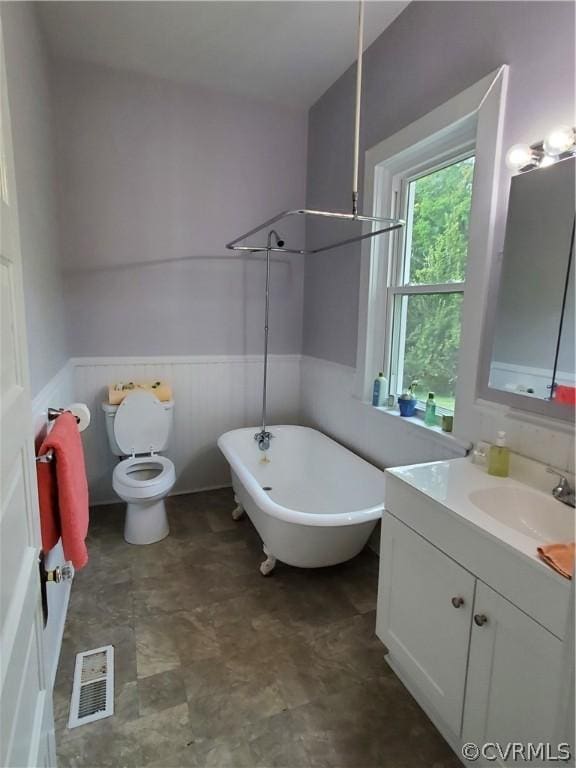 bathroom featuring toilet, vanity, and a bath