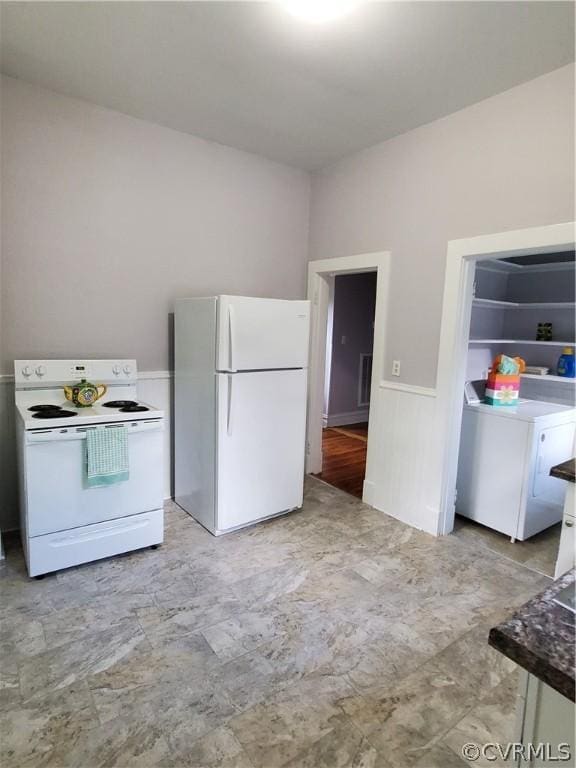 kitchen with white appliances, washer / dryer, and white cabinets