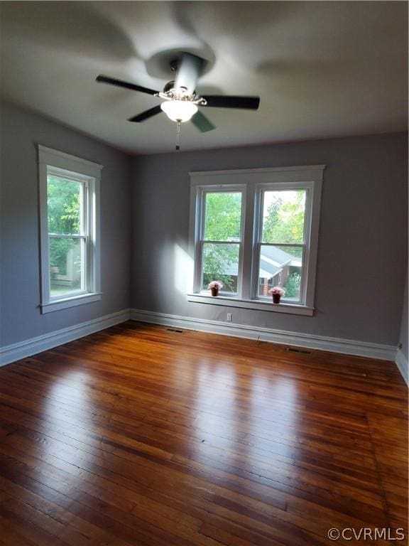 spare room featuring a wealth of natural light, dark hardwood / wood-style floors, and ceiling fan