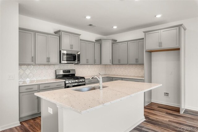 kitchen with dark wood-type flooring, appliances with stainless steel finishes, and light stone counters