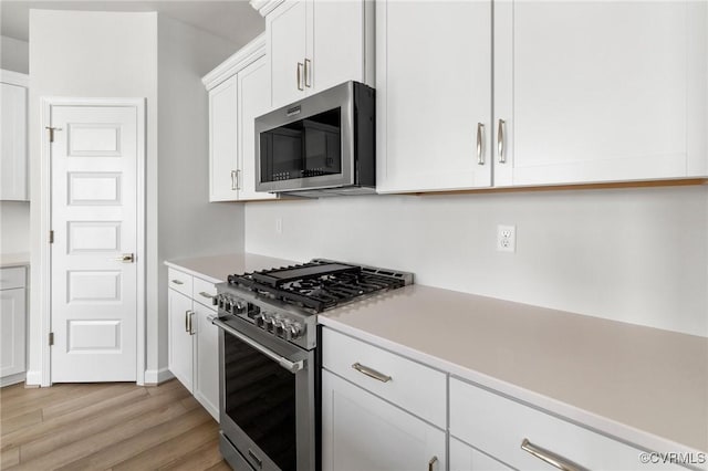 kitchen featuring white cabinets, appliances with stainless steel finishes, and light hardwood / wood-style flooring