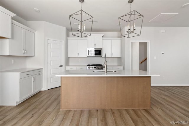 kitchen with sink, white cabinetry, and an island with sink