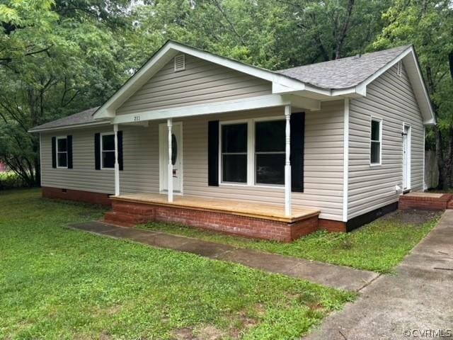 view of front of property featuring a porch, a view of trees, a front lawn, and crawl space