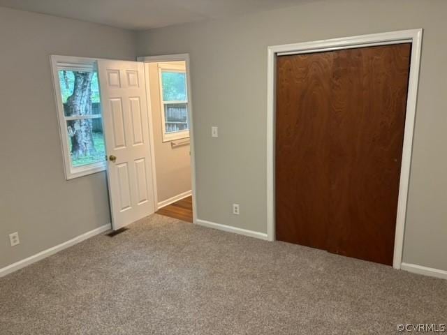 unfurnished bedroom featuring visible vents, carpet, baseboards, and a closet