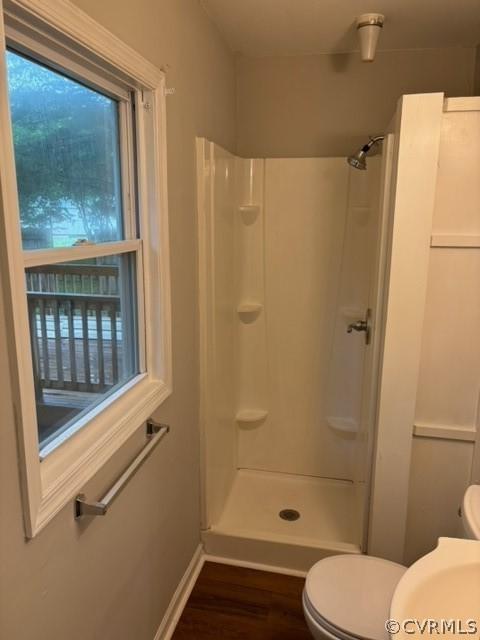 full bathroom featuring baseboards, toilet, walk in shower, and wood finished floors