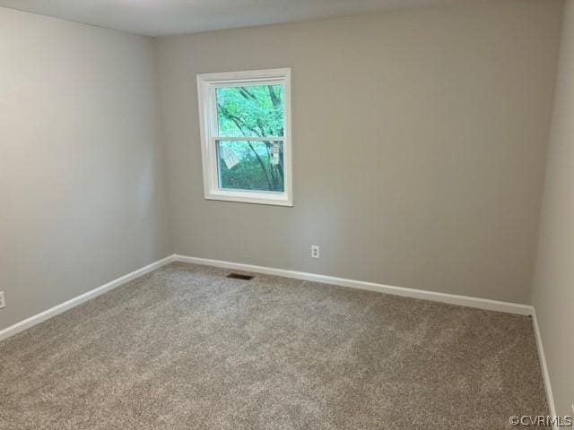 carpeted spare room with visible vents and baseboards