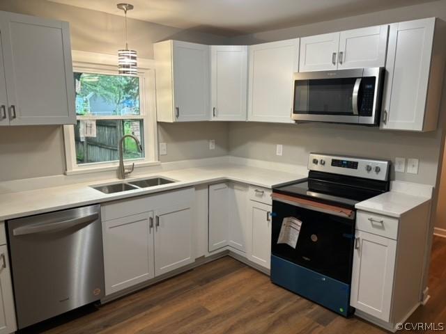 kitchen featuring a sink, stainless steel appliances, dark wood-style floors, and light countertops