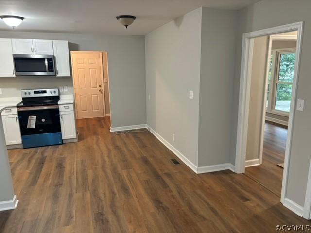 kitchen with dark wood finished floors, appliances with stainless steel finishes, white cabinetry, and light countertops