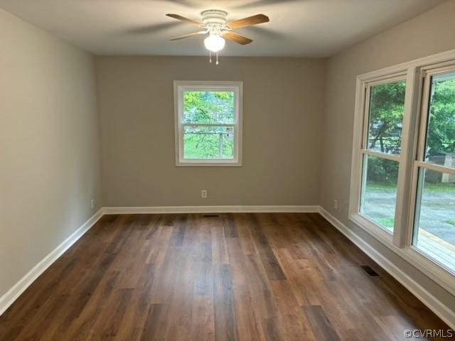 spare room featuring dark wood-type flooring, baseboards, and ceiling fan