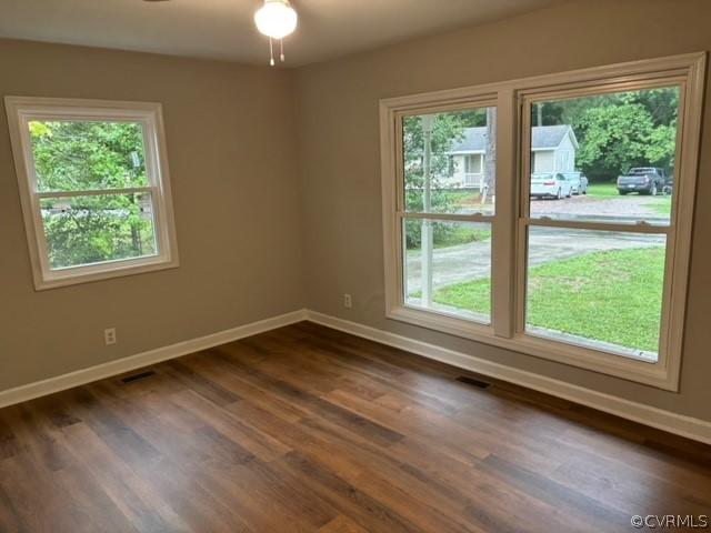 spare room featuring dark wood finished floors, visible vents, and baseboards