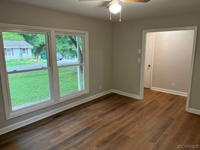 empty room featuring visible vents, baseboards, dark wood-style floors, and a ceiling fan