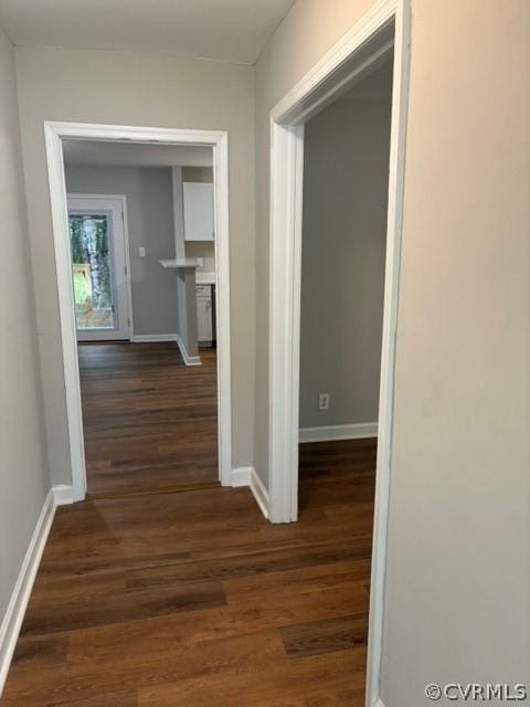 hall featuring baseboards and dark wood-style flooring