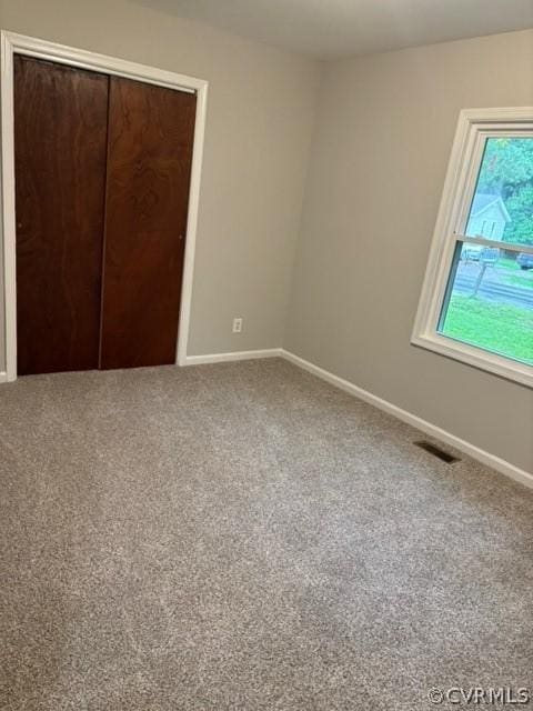 unfurnished bedroom with a closet, baseboards, carpet, and visible vents