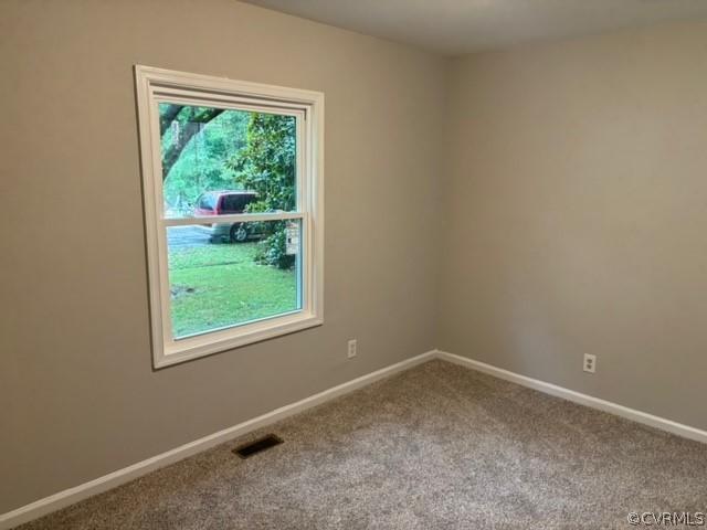 carpeted spare room featuring visible vents and baseboards