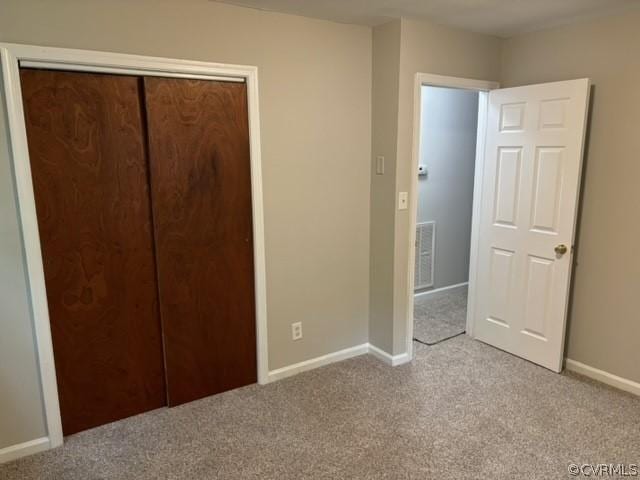 unfurnished bedroom with a closet, visible vents, light colored carpet, and baseboards