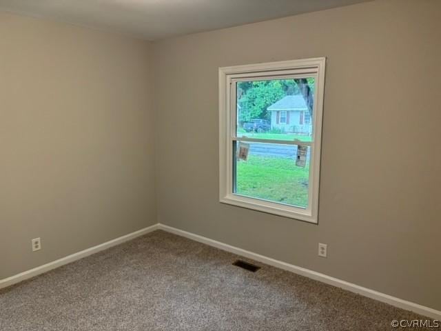 empty room featuring visible vents, carpet floors, and baseboards