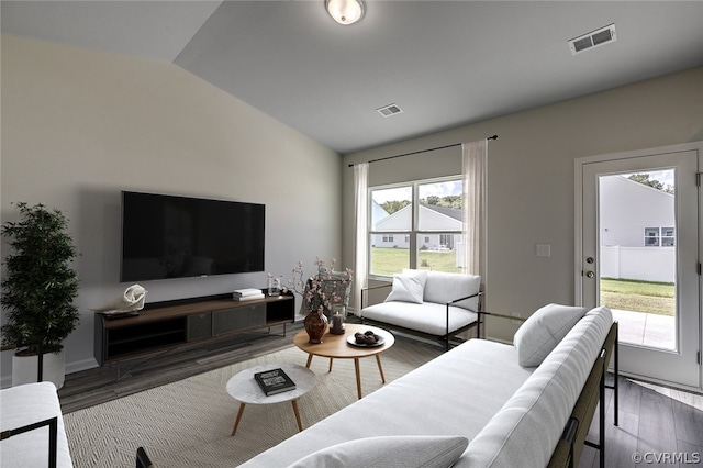 living room featuring a wealth of natural light, dark wood-type flooring, and vaulted ceiling