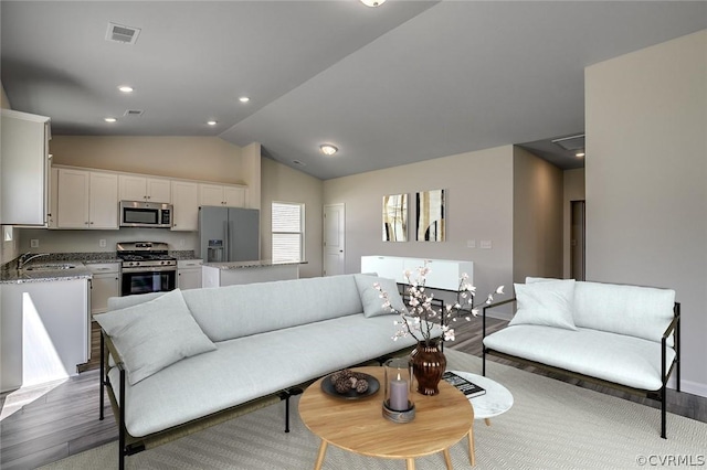 living room with vaulted ceiling, sink, and light hardwood / wood-style flooring