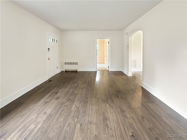 empty room with dark hardwood / wood-style floors and radiator