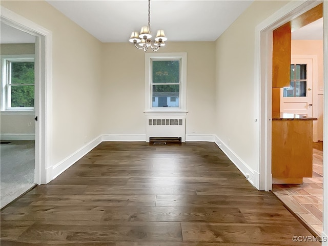 unfurnished dining area with radiator heating unit, dark hardwood / wood-style floors, and a notable chandelier