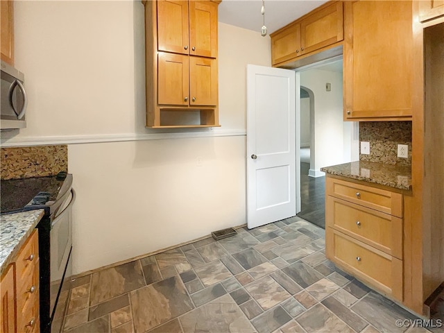 kitchen featuring black range with electric stovetop, backsplash, and light stone counters