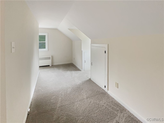 additional living space with vaulted ceiling, carpet floors, and radiator heating unit