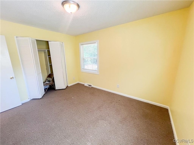 unfurnished bedroom featuring a closet, visible vents, carpet flooring, a textured ceiling, and baseboards