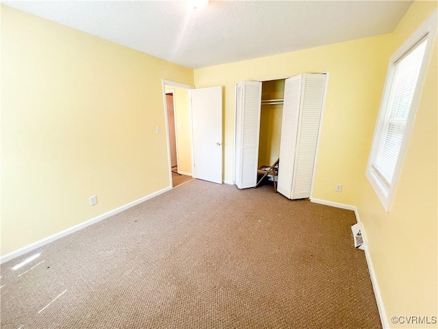 unfurnished bedroom with carpet floors, a closet, and baseboards