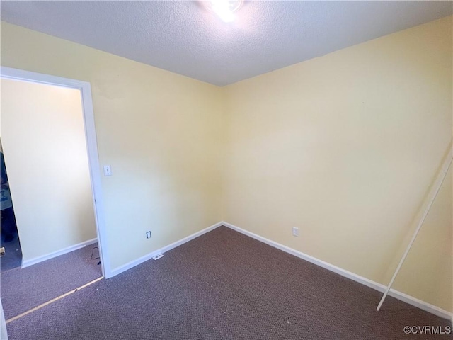 carpeted spare room featuring a textured ceiling and baseboards