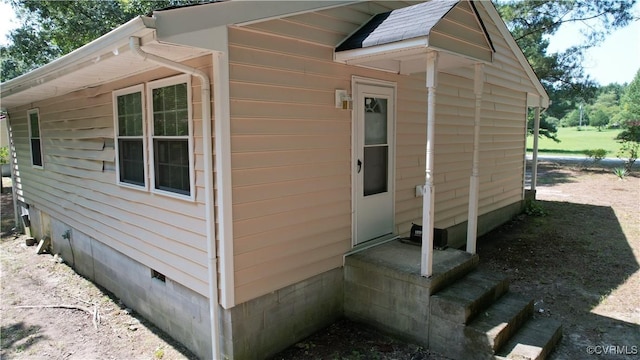 view of property exterior with a shingled roof, entry steps, and crawl space