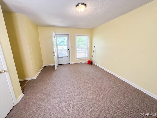 carpeted empty room featuring a textured ceiling and baseboards