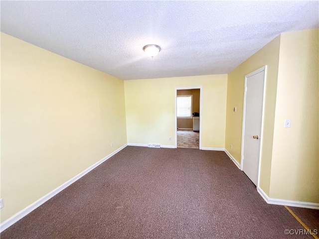 unfurnished room with visible vents, dark carpet, a textured ceiling, and baseboards