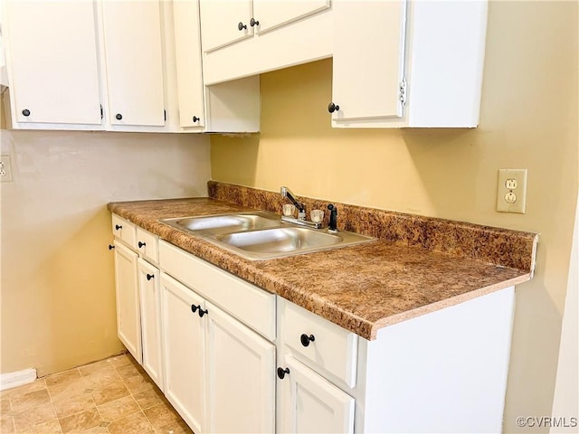 kitchen featuring white cabinetry and a sink