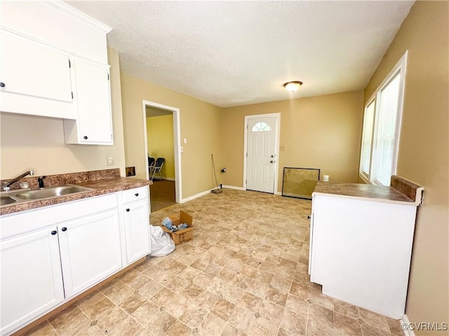 kitchen featuring dark countertops, a sink, white cabinetry, and a healthy amount of sunlight