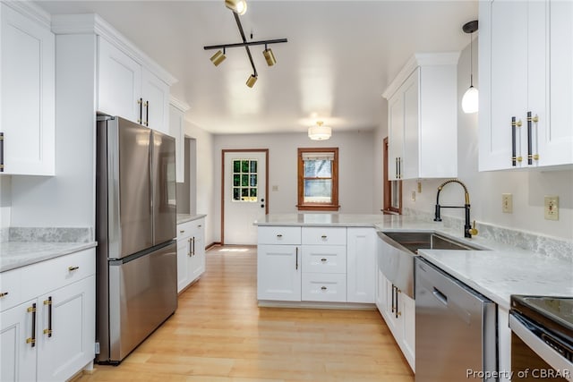 kitchen featuring appliances with stainless steel finishes, pendant lighting, kitchen peninsula, light wood-type flooring, and light stone countertops