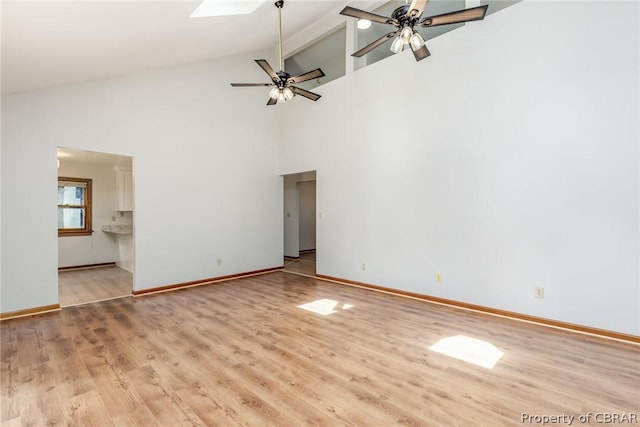 unfurnished living room with a skylight, light hardwood / wood-style flooring, beamed ceiling, and ceiling fan