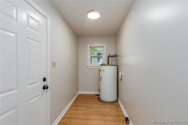 laundry room featuring water heater and light hardwood / wood-style flooring