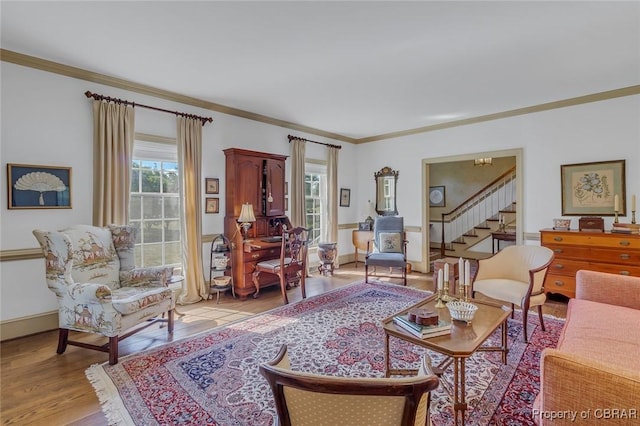 living area featuring stairway, light wood-style flooring, crown molding, and baseboards