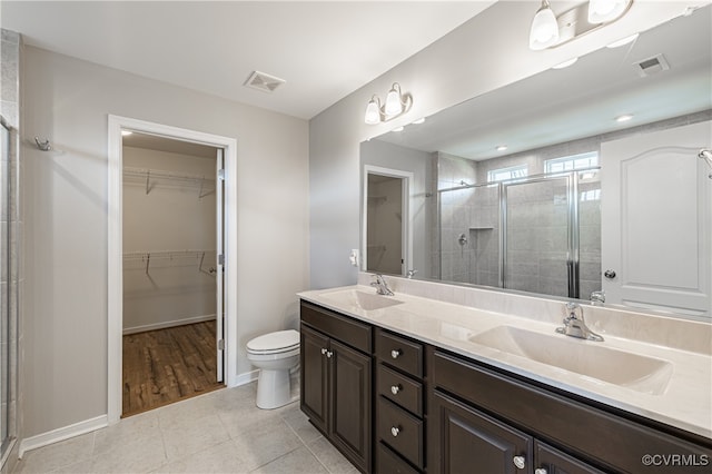 bathroom with tile patterned flooring, a shower with shower door, toilet, and vanity