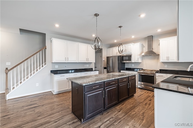 kitchen with hardwood / wood-style floors, a center island, sink, appliances with stainless steel finishes, and wall chimney range hood