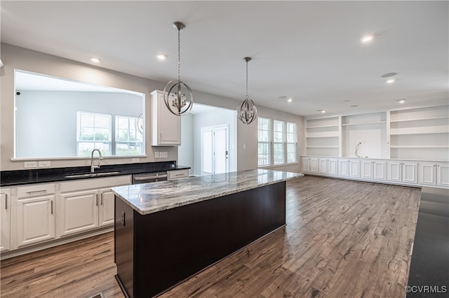 kitchen with light wood-type flooring, a center island, sink, and dark stone counters