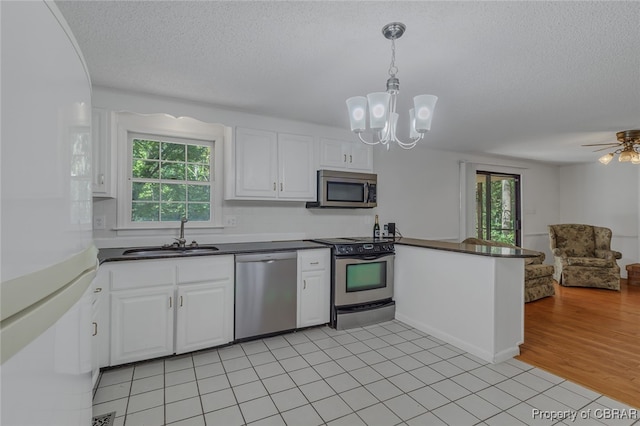 kitchen featuring white cabinetry, light tile patterned floors, ceiling fan with notable chandelier, stainless steel appliances, and sink