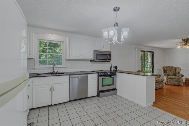 kitchen with dark countertops, open floor plan, white cabinets, and stainless steel appliances