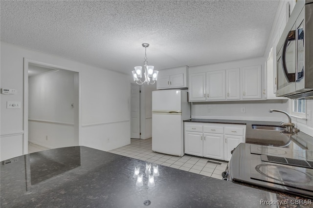 kitchen featuring white fridge, light tile patterned floors, an inviting chandelier, white cabinets, and pendant lighting