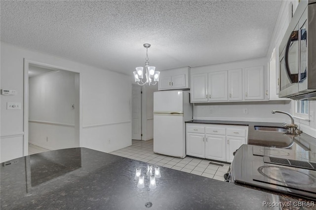 kitchen featuring electric range, freestanding refrigerator, a sink, white cabinets, and stainless steel microwave