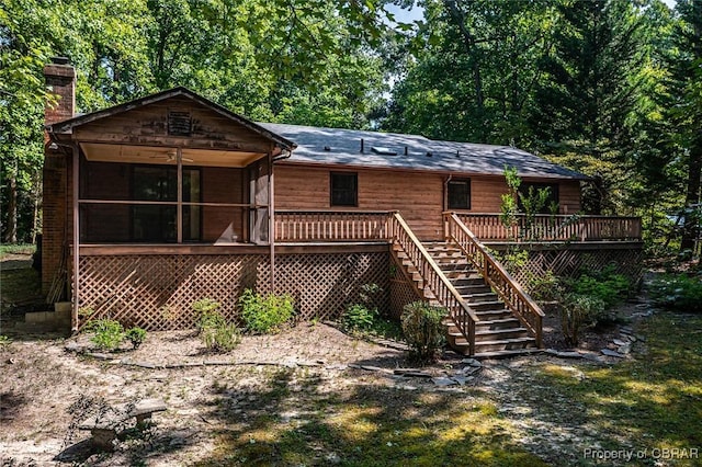 back of house featuring a wooden deck, stairway, a chimney, and a sunroom