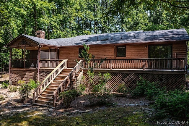 rear view of house with a wooden deck, stairway, and a chimney