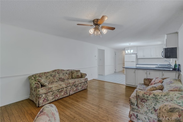 living room featuring light tile patterned flooring, sink, a textured ceiling, and ceiling fan